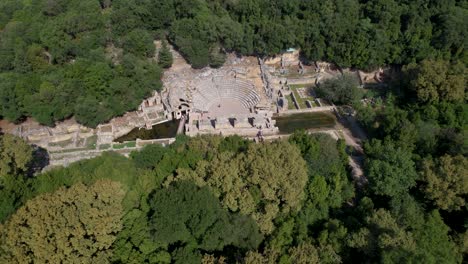 Ancient-Roman-Amphitheater-and-Buildings-Amidst-Lush-Greenery-in-Butrint-Archaeological-Park-in-Albania,-Aerial-View