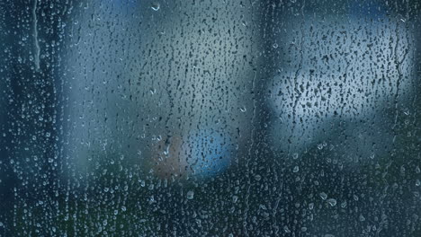 Closeup-raindrops-trickling-down-on-wet-clear-window-glass-on-a-rainy-day