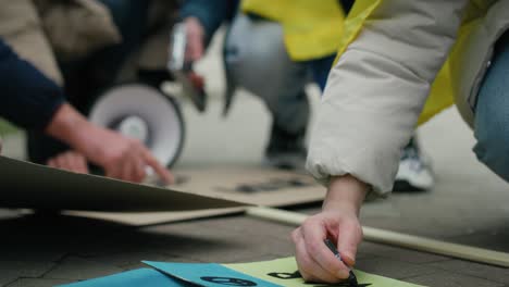 Caucasian-woman-preparing-cardboard-banners-for-manifest-against-Ukrainian-war.