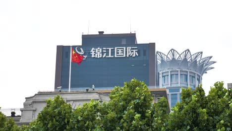 Shanghai-Chinese-flag-slowly-moving-in-the-wind-with-commercial-business-building-in-the-background