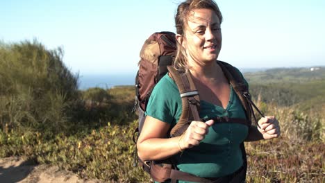 Peaceful-middle-aged-woman-wearing-camping-backpack