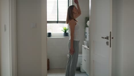 Side-view-of-young-caucasian-woman-standing-in-the-domestic-bathroom-and-stretching.