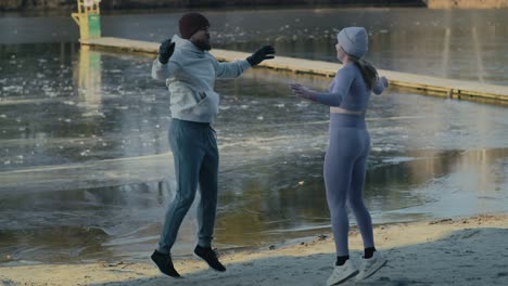 Wide-shot-of-adult-caucasian-couple-warming-up-before-winter-swimming.