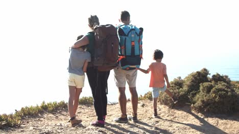 Family-of-active-tourists-standing-on-footpath-at-cliff