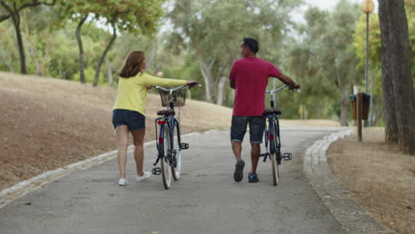 Long-shot-of-Caucasian-couple-walking-with-bicycles-in-summer