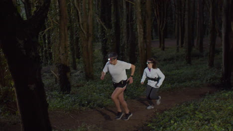 Man-and-woman-running-on-forest-trail-at-dusk