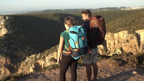 Couple-of-hikers-with-camping-backpacks-standing-at-cliff