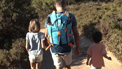 Dad-and-two-kids-walking-on-path-outdoors