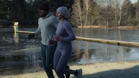 Adult-caucasian-couple-jogging-to-warm-up-before-winter-swimming.