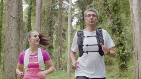 Happy-man-and-woman-running-in-forest-and-talking