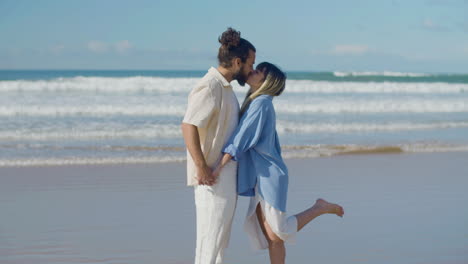 Romantic-couple-standing-at-seashore,-kissing
