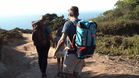 Family-of-hikers-with-backpacks-walking-on-path-outdoors