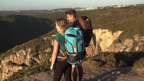 Couple-of-hikers-with-camping-backpacks-standing-at-cliff