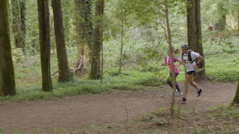 Man-and-woman-in-sportswear-running-on-trail-in-forest