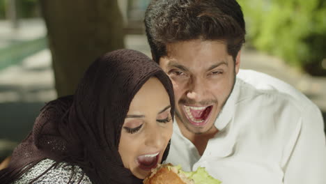 Close-up-of-young-muslim-couple-having-fun,-eating-sandwich.