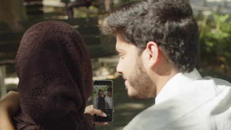 Close-up-of-young-muslim-couple-doing-selfie-outside.