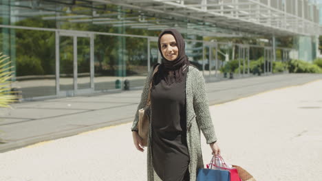 Hübsche-Muslimische-Frau,-Die-An-Einem-Warmen-Sommertag-Einkaufstüten-Schwingt.
