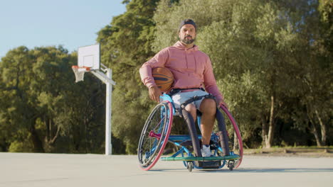 Bearded-middle-aged-man-in-sports-wheelchair-at-basketball-court