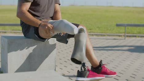 Mittlere-Nahaufnahme-Eines-Männlichen-Athleten,-Der-Eine-Beinprothese-Anzieht.