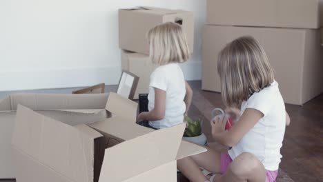 Adorable-girls-unpacking-things-in-new-apartment