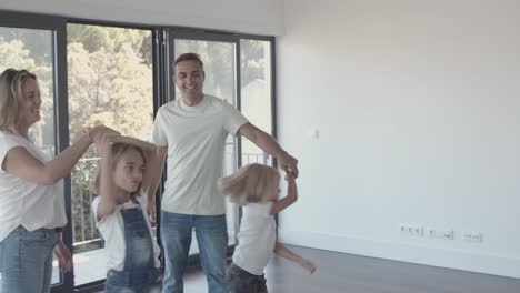 Happy-parents-and-active-kids-having-fun-in-new-empty-apartment