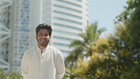 Portrait-of-young-muslim-man-smiling-at-camera-on-sunny-day.