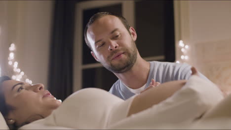 Pregnant-woman-lying-on-bed-and-looking-at-husband