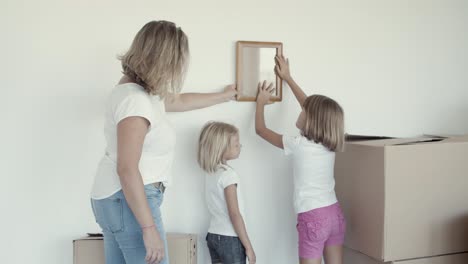 Two-girls-and-their-mom-choosing-place-on-wall-for-picture