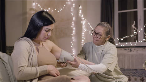 Asian-doula-measuring-blood-pressure-of-pregnant-woman