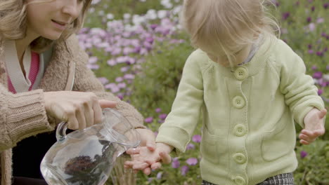 Mother-pouring-water-from-jug-on-daughters-hands-outdoor