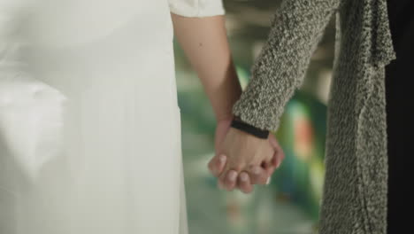 Close-up-of-young-couple-holding-hands,-interlocking-fingers.