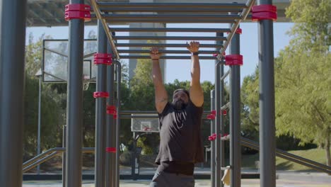 Strong-Caucasian-man-working-out-on-monkey-bars-in-park.