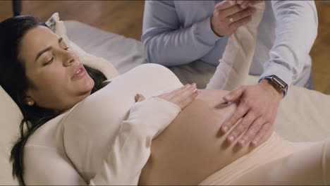 Mujer-Embarazada-Acostada-En-La-Cama-Y-Sosteniendo-La-Mano-De-Su-Marido.
