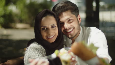 Glückliches-Muslimisches-Paar,-Das-An-Einem-Sonnigen-Tag-Sein-Mittagessen-Der-Kamera-Zeigt.