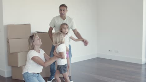 Fröhliche-Eltern-Und-Zwei-Mädchen-Tanzen-In-Ihrer-Neuen-Wohnung