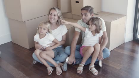 Glückliches-Familienpaar-Und-Zwei-Töchter,-Die-Auf-Dem-Boden-Sitzen