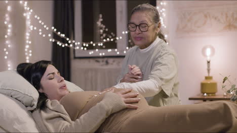 Asian-doula-stroking-belly-of-pregnant-woman-at-home
