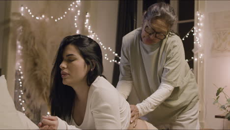 Asian-doula-massaging-pregnant-woman-back-at-home