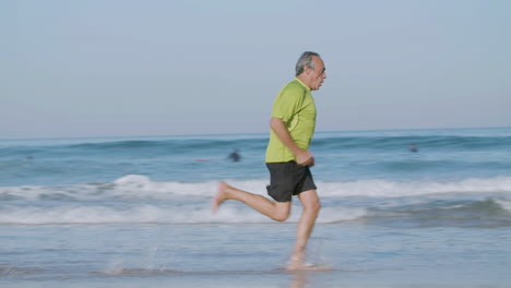 Focused-man-running-at-fast-pace-along-ocean-coast-on-summer-day