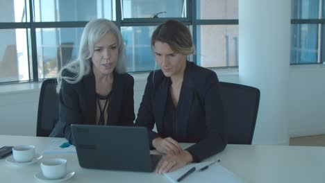 Focused-female-colleagues-using-laptop-together