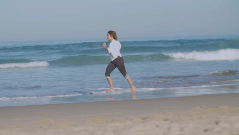 Confident-woman-running-at-fast-pace-on-sandy-beach