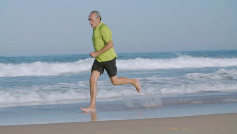 Confident-man-running-barefoot-fast-on-sandy-beach