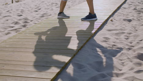 Man-and-woman-standing-on-wooden-path-on-beach-and-exercising