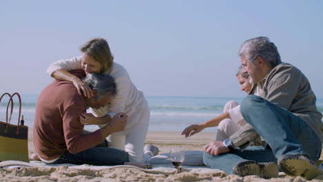 Senior-people-having-fun-while-sitting-on-ocean-shore