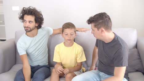 Pensive-boy-sitting-on-couch-with-his-two-dads