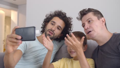 Positive-homosexual-parents-and-kid-using-cell-for-video-call