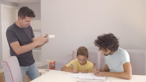 Focused-boy-doing-school-home-task-with-help-of-two-dads