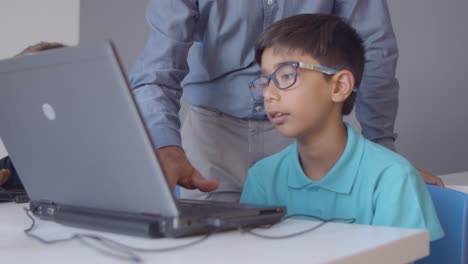 Teacher-helping-worried-schoolboy-to-do-task