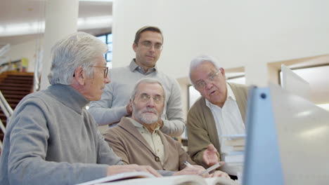 Ältere-Männer-Und-Lehrer-Schauen-Auf-Den-Laptop-Bildschirm-In-Der-Bibliothek