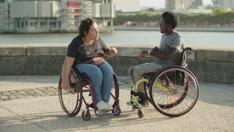 Cheerful-friends-using-wheelchairs-dancing-at-quayside